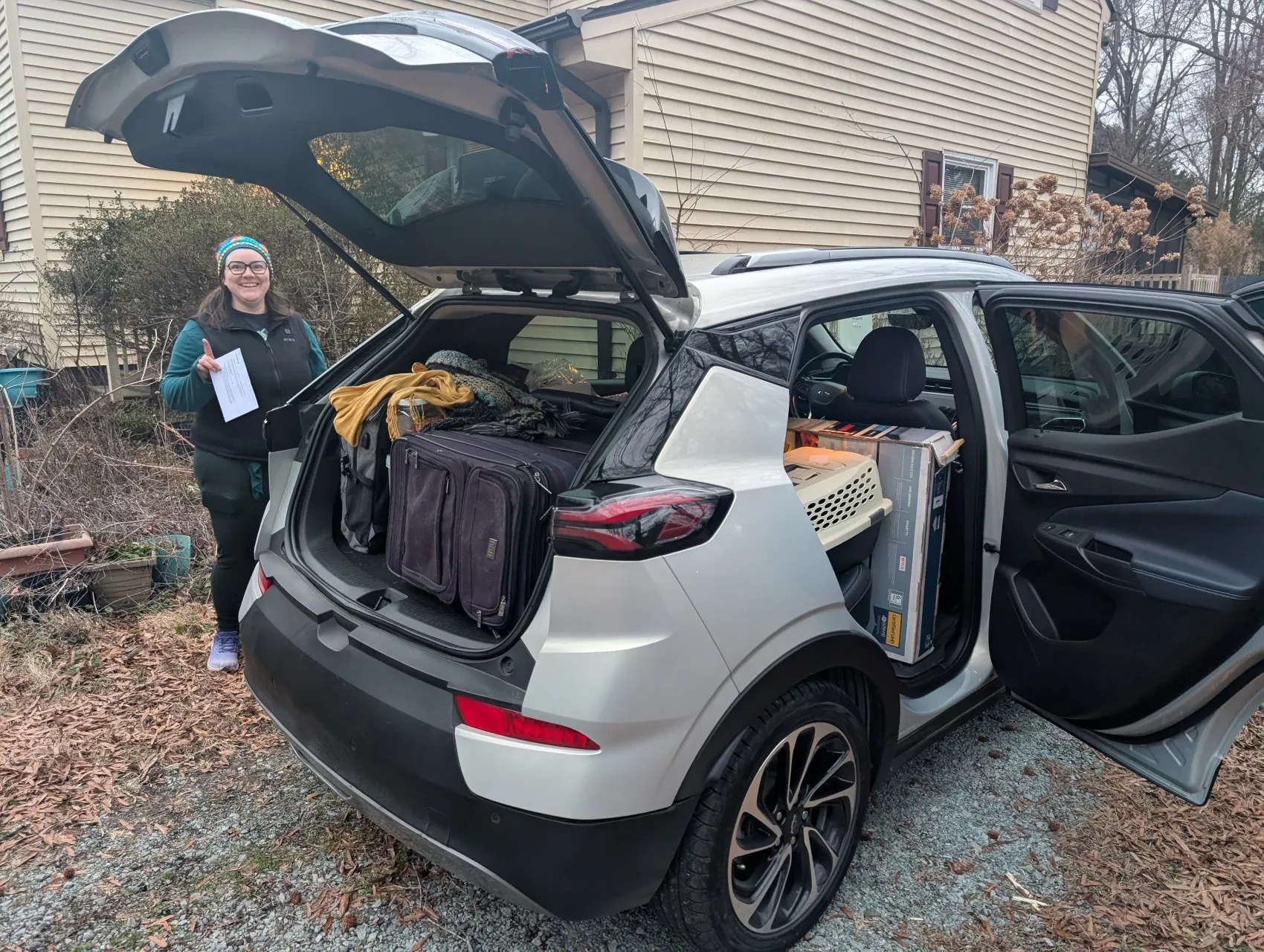 Our silver Bolt EUV, loaded completely full with boxes, suitcases, and a cat carrier. Holly is next to it, looking excited.